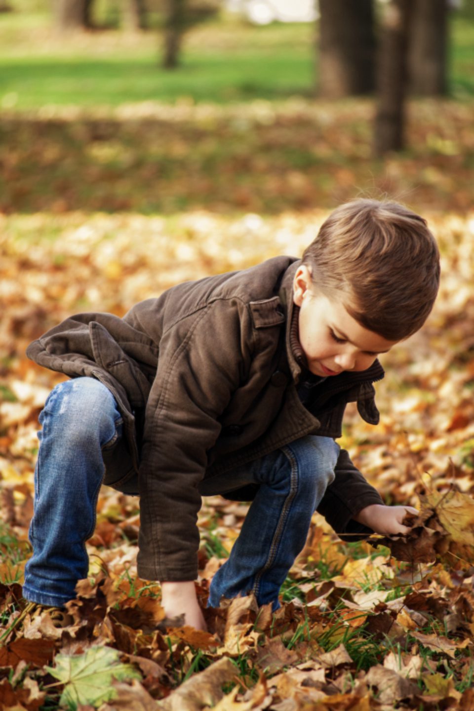 Een jongetje speelt buiten tussen de herfstbladeren